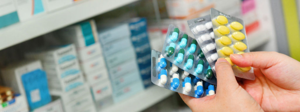 person's hands holding packages with pills